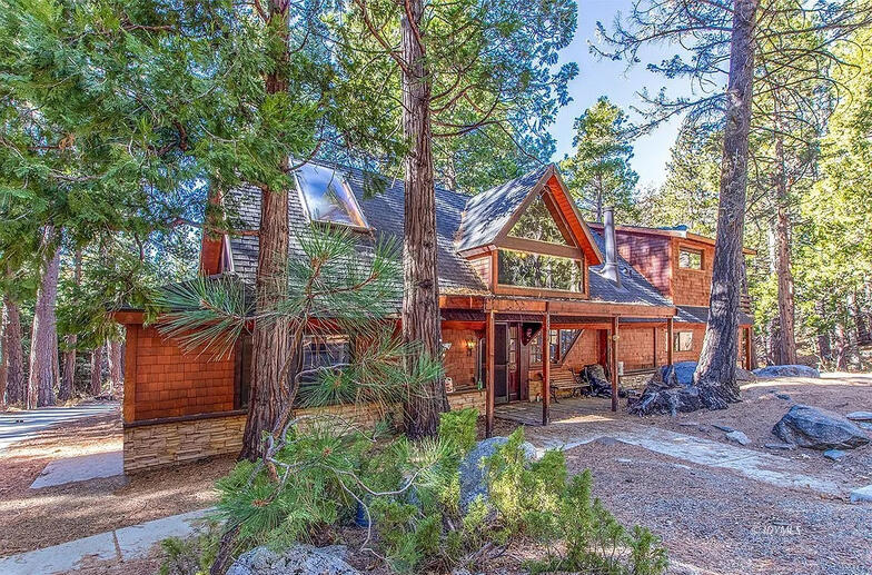 A-frame lodge surrounded by mountains and forest.